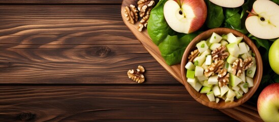 Fototapeta premium Top view of a wooden table with a delicious Waldorf salad, made with lettuce, green apples, walnuts, and celery. Ample empty space for copy.