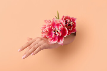 Female hand with tulips visible through hole in nude paper