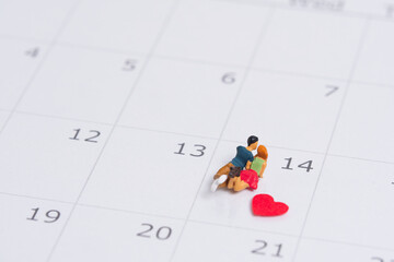 Junges verliebtes Paar steht bei der Nummer 14 auf einem Kalender im Monat Februar wegen Valentinstag , Miniaturfiguren szene