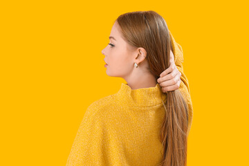 Fashionable young woman in knitted sweater on yellow background - obrazy, fototapety, plakaty