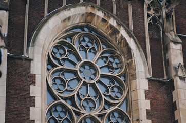Large old vintage openwork round window with stained glass on facade of the building. Baroque and Gothic architecture. Church of St. Olga and Elizabeth. Lviv, Ukraine.