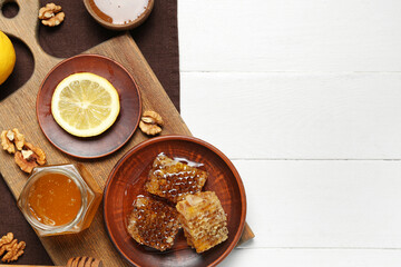 Jar of sweet honey, combs and lemon on white wooden background