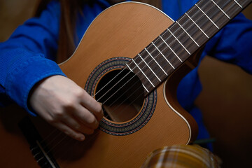 Fototapeta premium Close up professional classical guitar. Teenager hands in blue shirt playing. Music lesson, art education.