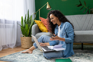 Young beautiful woman sitting on the floor at home in the living room, student studying remotely, using laptop to watch webinar and video course, online call consultation with teacher. - obrazy, fototapety, plakaty