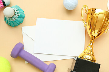 Blank card with gold cup and sports equipment on beige background