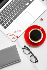 Composition with laptop, coffee, eyeglasses and notepad on light background