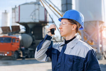 Worker use radio walkie talkie background concrete mixer truck. Construction man in hardhat working...