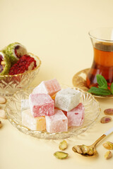 Bowl with tasty Turkish delight on yellow background