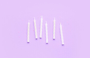 White birthday candles on lilac background
