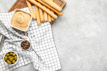 Bowl with tasty hummus and Italian Grissini on light background