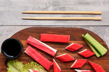 Board with tasty crab sticks and sauce on light wooden background, closeup © Pixel-Shot