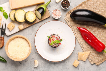 Plate with tasty baked Eggplant Parmesan and ingredients on grunge background