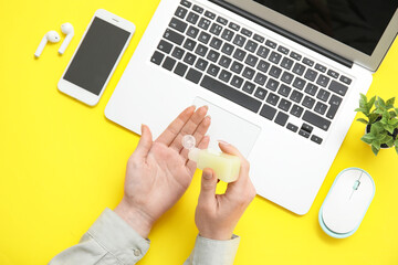 Woman applying hand sanitizer at yellow table in office