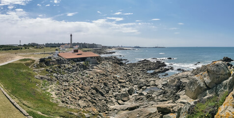 View at the Blue Beach or praia Azul and Casa de Chá da Boa Nova, a building Built on the rocks, front to the sea, Leça da Palmeira urban buildings and lighthouse as background