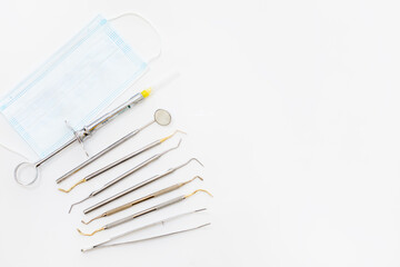 Naklejka premium Dental examination concept. Tooth shaped holder, dentist tools, toothbrush and face mask on white background, flat lay.