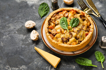 Mushroom pie with spinach leaves and champignons on dark grey grunge background
