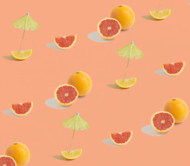 A seamless pattern made of isolated grapefruits, oranges and lemons with a cocktail parasol on an orange background. Copy space, minimal fruit concept. Healthy nutrition.