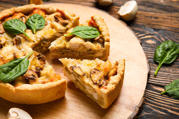 Pieces of mushroom pie with spinach leaves and champignons on brown wooden table