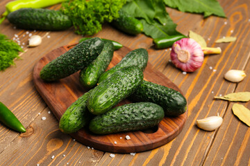 Board with fresh cucumbers for preservation on wooden background