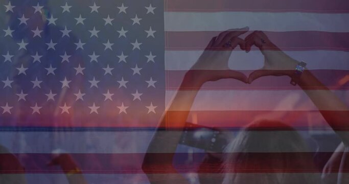 Animation of flag of america over hands of crowd at concert making heart shape and waving
