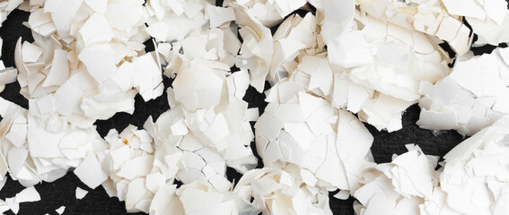 A pile of eggshells on a dark background. View from above. Panorama.