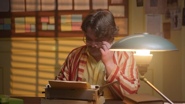 Inspired famous writer in retro style in robe writes poem or letter on mechanical typewriter in office or at home in study. journalist with glasses and mustache is composing article and thinking.