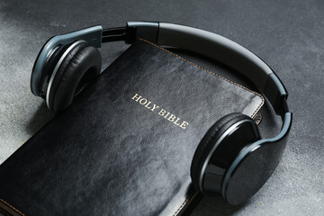 Holy Bible with headphones on grunge background, closeup