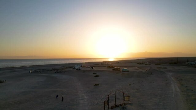 Trailer camp on the shore of the deserted coast of Bombay. Drone footage. Panoramic aerial view to the Southern California Salton Sea landscape at the sunset.