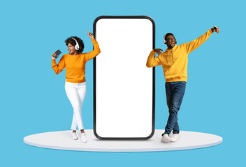 Two people in yellow enjoying music with headphones by giant phone