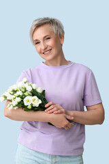 Mature woman with beautiful roses on light background