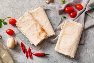 Board with lavash and fresh vegetables on grey background