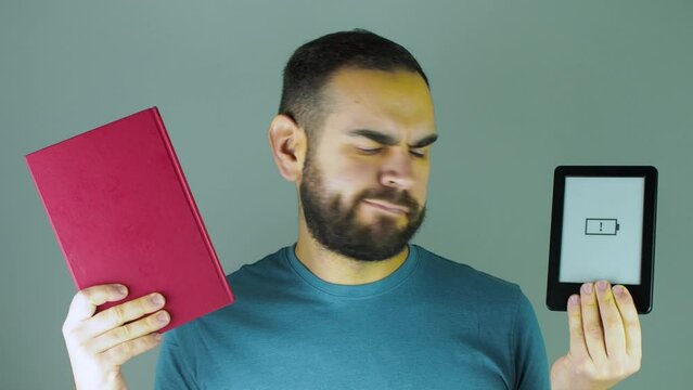 young bearded man choosing between ebook or paper book