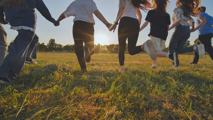 Young boys running at sunset across the field holding hands. - obrazy, fototapety, plakaty