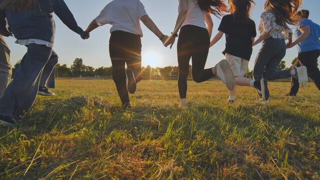 Young boys running at sunset across the field holding hands.