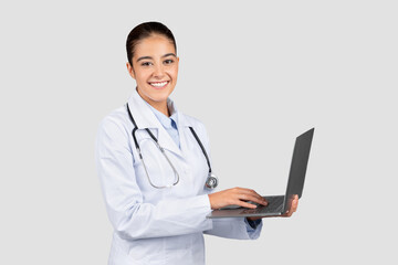 Professional young Caucasian millennial doctor using a laptop, possibly for patient records