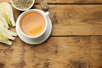 Fennel tea in cup, seeds and fresh vegetable on wooden table, flat lay. Space for text