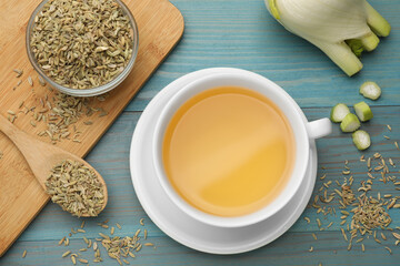 Fennel tea in cup, seeds and fresh vegetable on light blue wooden table, flat lay