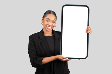 Delighted African American businesswoman showcasing an oversized blank smartphone screen