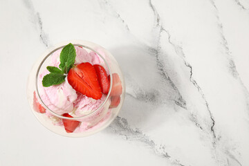 Glass bowl of strawberry ice cream with mint on grunge background