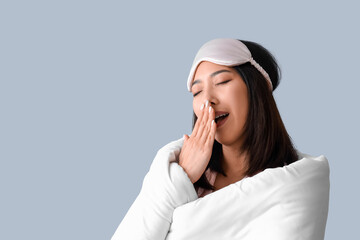 Beautiful Asian woman with sleeping mask and blanket on grey background, closeup