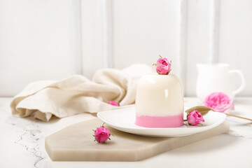 Fototapeta na wymiar Plate of panna cotta with beautiful pink rose flowers on white table