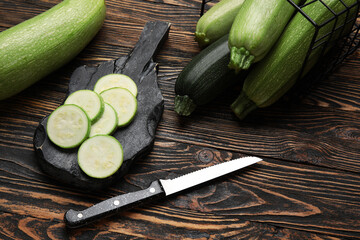 Board of slices and basket with fresh green zucchini on wooden background