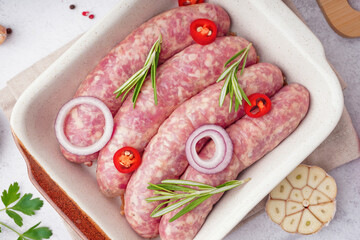 Baking dish with raw homemade sausages on light background