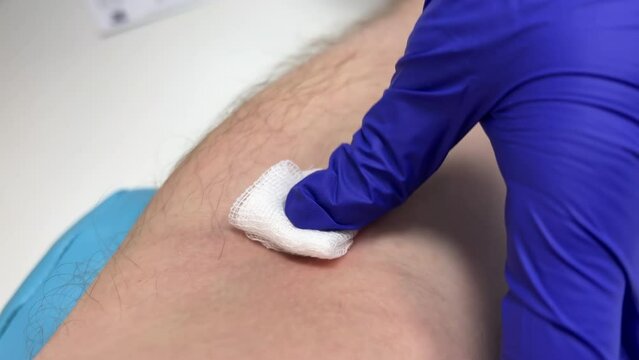 Nurse applies a bandage to a patient's antecubital vein after drawing venous blood. Close-up shot