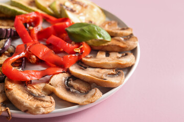 Plate with tasty grilled vegetables on pink background
