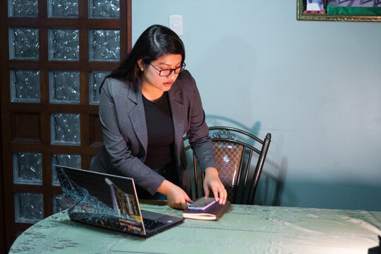 Caucasian Woman in Gray Jacket Sitting Near Table Talking on Phone, Laptop ,Digital Gray Navigating Between Technology and Comfort