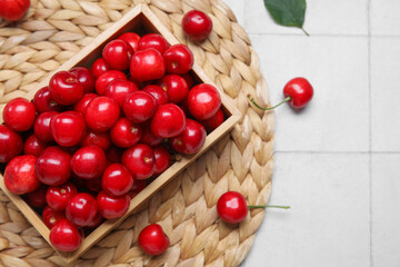 Wooden box with sweet cherries on white tile background