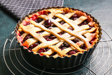 Baking dish with tasty cherry pie on dark background