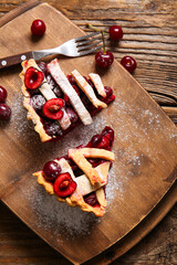 Board with tasty cherry pie on wooden background