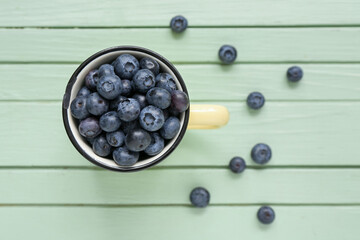 Cup with fresh blueberry on color wooden background
